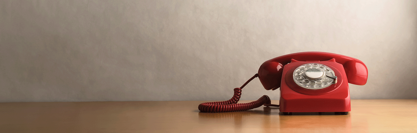 A bright red telephone sitting by itself on a table