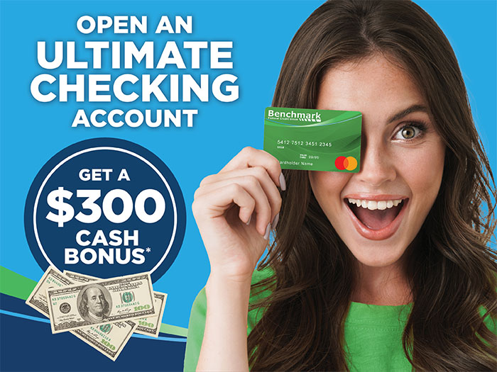 Woman holding a Benchmark debit card over her eye while smiling.
