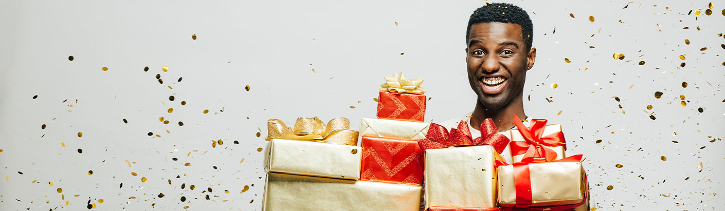 African American man smiling while holding Christmas gifts.