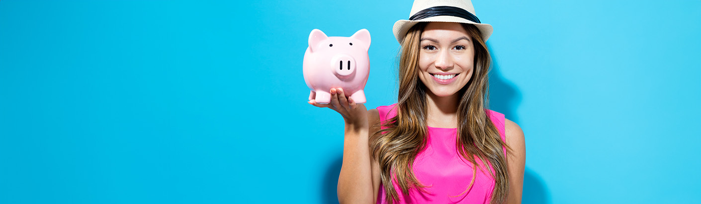 Woman in a pink dress holding a pink piggy bank in her right hand in front of a light blue background.