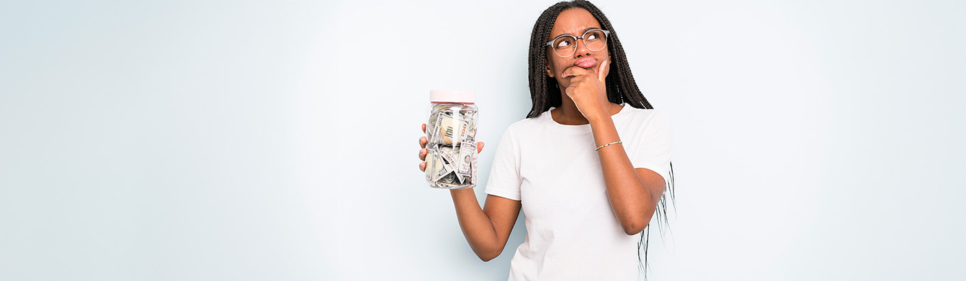 Woman holding up a jar of cash as she thinks to herself.